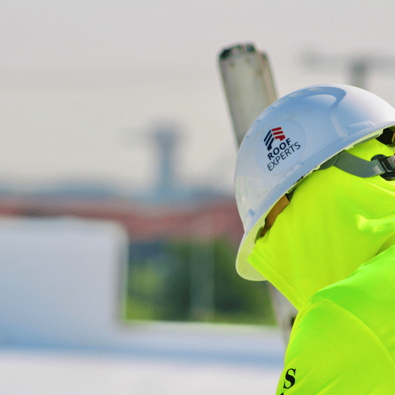 Roof Experts roofer wearing high-vis uniform inspects TPO roof