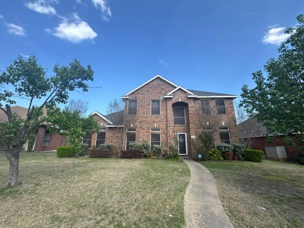 Completed shingle roof on a two-story brick home in Garland, TX